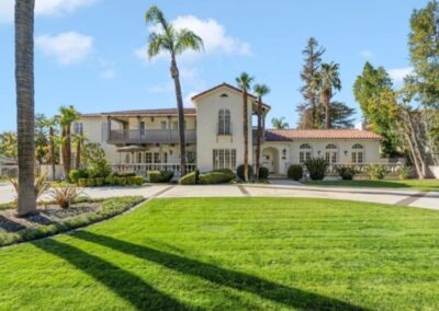 Spacious home surrounded by palm trees and lush green grass.