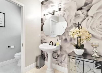 A bathroom with a sink and a large floral wallpaper, creating a vibrant and elegant atmosphere.