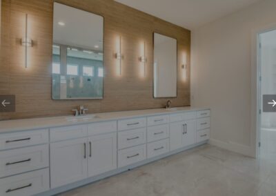 A bathroom with white cabinets and a large mirror.